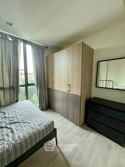 Modern bedroom with large window, stylish wardrobe, and sleek dresser.