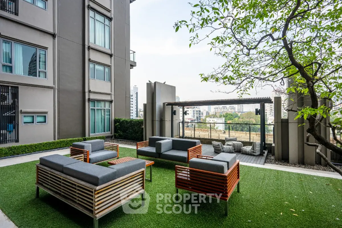 Modern apartment building with stylish outdoor seating area and lush greenery.