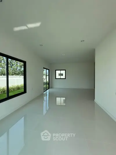 Spacious empty room with large windows and glossy white tiles, perfect for customization.