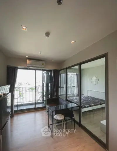 Modern apartment with glass-walled bedroom and balcony view, featuring sleek furniture and ample natural light.