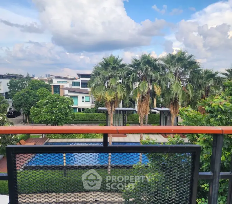 Stunning view of modern homes with lush greenery and a pool from a balcony.