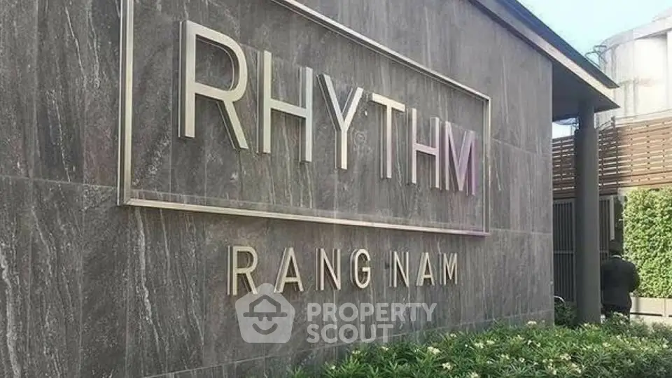Modern building exterior with stylish signage and lush greenery at Rhythm Rangnam.