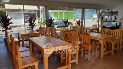 Spacious dining area with wooden furniture and large windows for natural light.