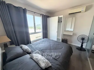 Modern bedroom with large window and air conditioning, featuring stylish gray decor and ample natural light.