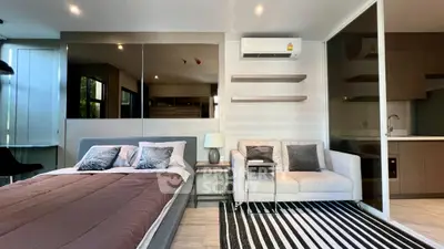 Modern studio apartment with stylish decor, featuring a cozy bed, sleek sofa, and open kitchen layout.