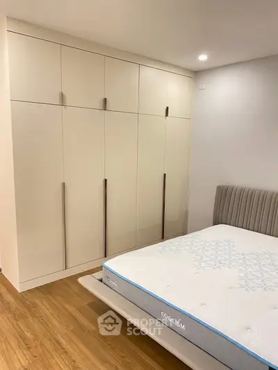Modern bedroom with sleek wardrobe and comfortable mattress on wooden flooring.