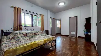 Spacious bedroom with wooden flooring and large window for natural light