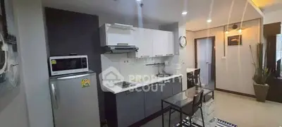 Modern kitchen with sleek cabinetry and dining area in stylish apartment.