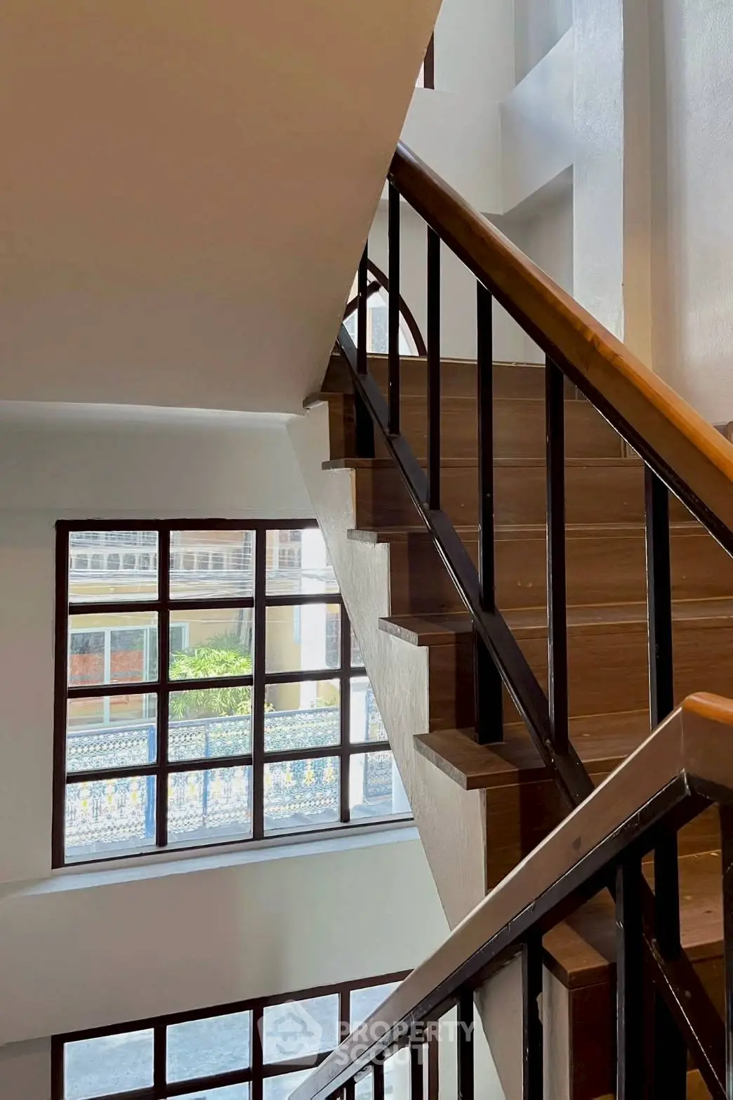 Elegant staircase with wooden steps and large windows in a modern building