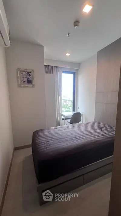 Cozy bedroom with modern decor and large window offering natural light and scenic views.