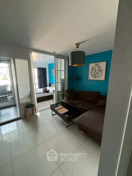 Modern living room with blue accent wall and cozy seating area in stylish apartment.