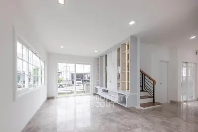 Spacious modern living room with large windows and elegant staircase