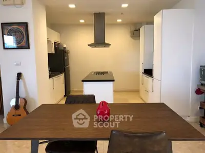 Modern kitchen with island and dining area, featuring sleek cabinetry and contemporary decor.