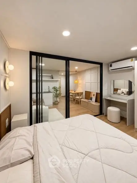Modern bedroom with sliding glass doors leading to a stylish living area, featuring contemporary decor and lighting.