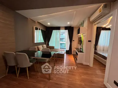Modern living room with dining area, featuring sleek furniture and large windows for natural light.