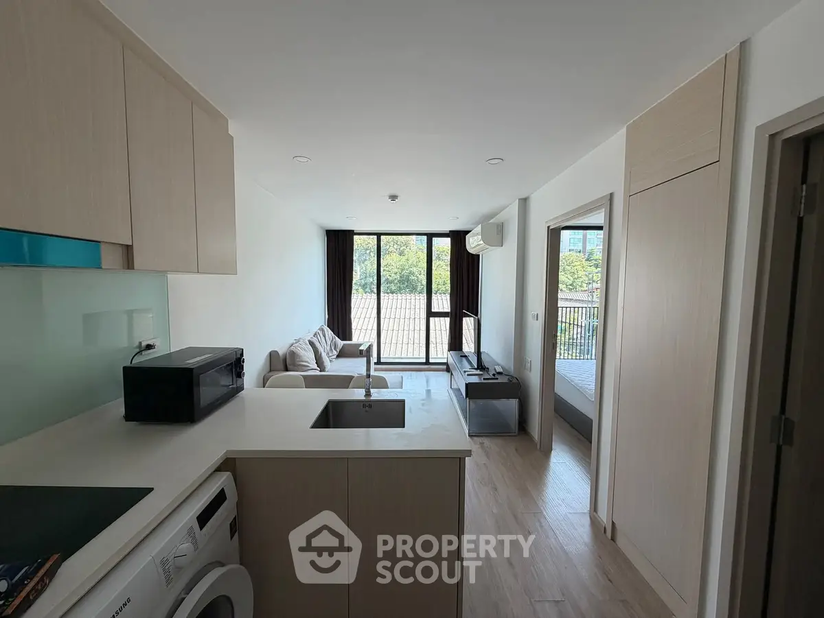 Modern open-plan living room with kitchen, featuring sleek design and natural light.