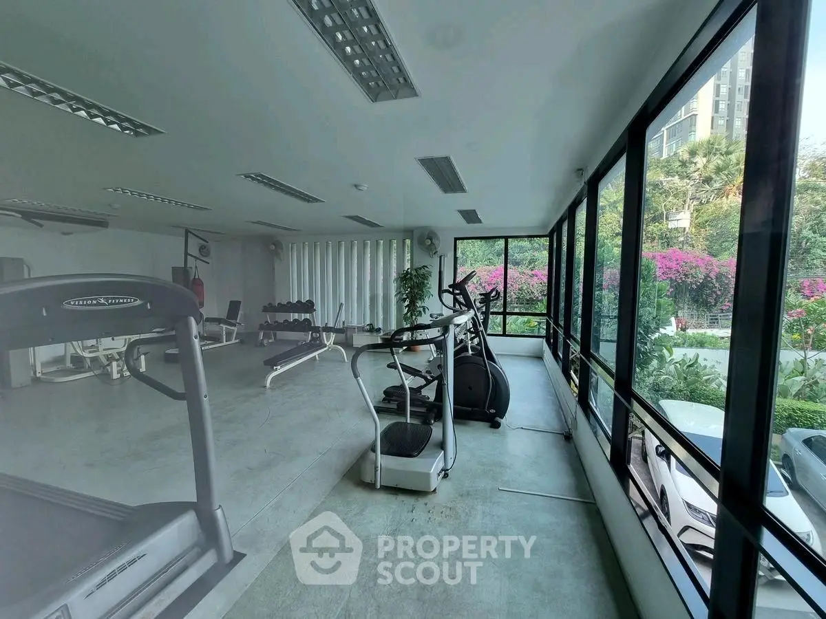 Spacious gym with modern equipment and large windows offering garden views.