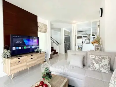 Modern living room with sleek TV setup and cozy sectional sofa, open layout leading to kitchen.