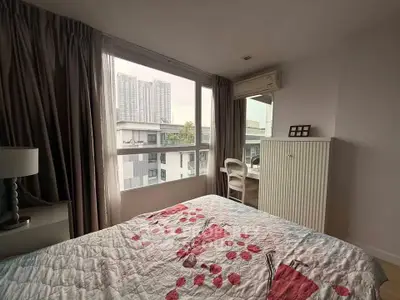 Cozy bedroom with large windows offering city views and modern furnishings.