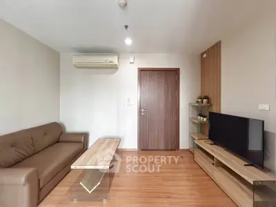 Modern living room with sleek furniture and wooden flooring, featuring a comfortable sofa and flat-screen TV.