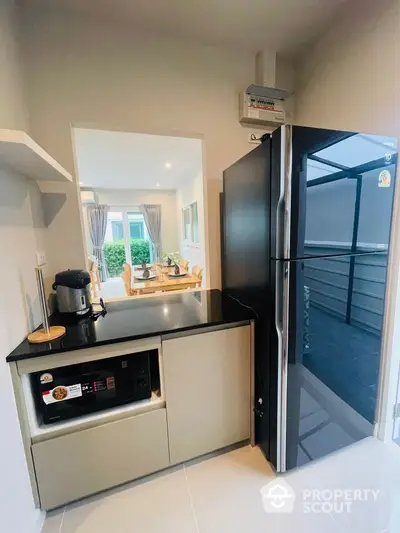 Modern kitchen with sleek appliances and open layout leading to dining area.