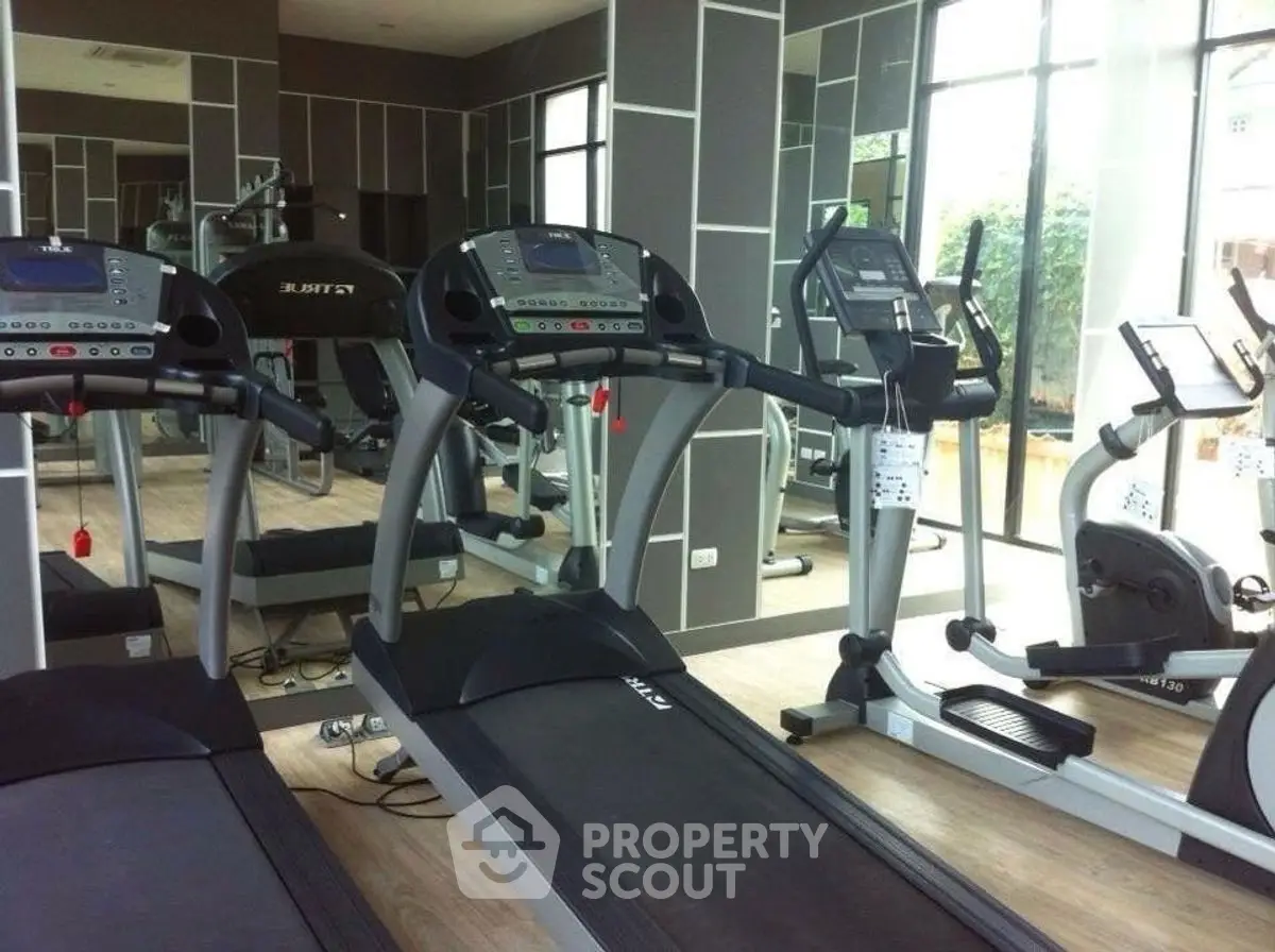 Modern gym with state-of-the-art fitness equipment and large windows for natural light.