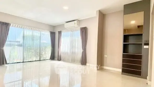 Spacious living room with large windows and modern air conditioning unit.