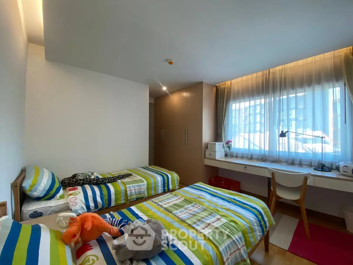 Bright and cozy bedroom with twin beds and large window, perfect for a comfortable stay.