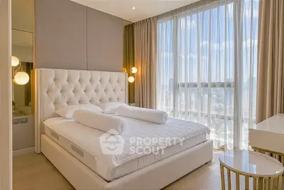 Luxurious bedroom with elegant decor and floor-to-ceiling windows offering stunning city views.
