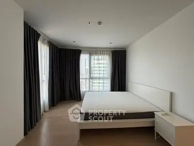 Spacious bedroom with large windows and modern minimalist design in a luxury apartment.