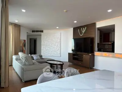 Spacious modern living room with elegant decor and open layout, featuring a large TV and comfortable seating.