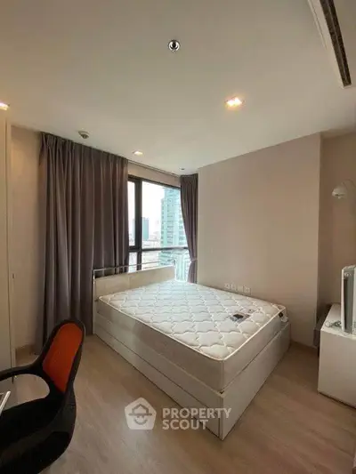 Modern bedroom with large window and city view, featuring a comfortable bed and sleek furniture.