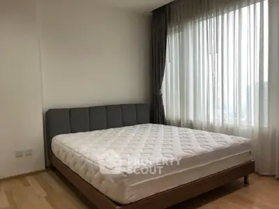 Spacious bedroom with large window and modern bed in a bright apartment.
