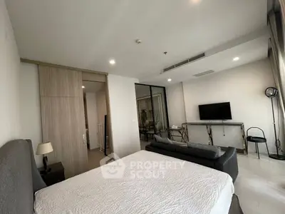 Modern bedroom with stylish decor and TV, featuring a cozy bed and sleek furniture.