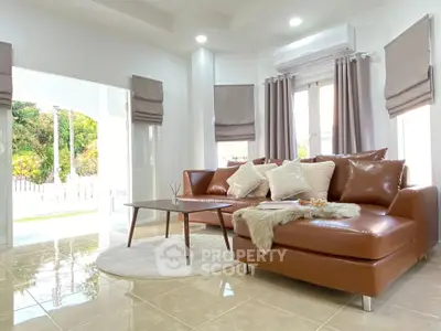 Luxurious living room with leather sofa, elegant decor, and abundant natural light in a modern home.