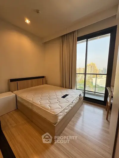 Modern bedroom with large window offering stunning city view, featuring a comfortable bed and sleek wooden flooring.