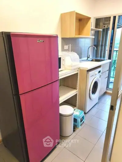 Modern kitchen with pink fridge, washing machine, and open layout design.