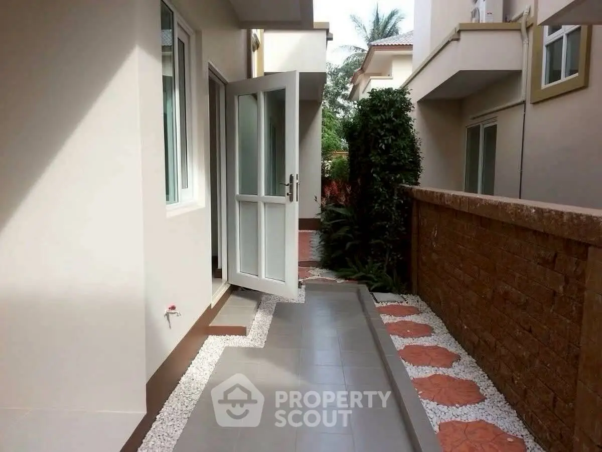 Charming exterior walkway with modern design and lush greenery in a residential property.