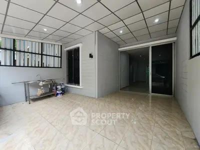 Spacious tiled area with modern ceiling lights and sliding glass door, perfect for versatile use.