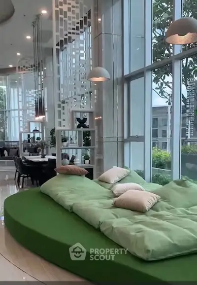 Luxurious modern living room with large windows and stylish green seating area.