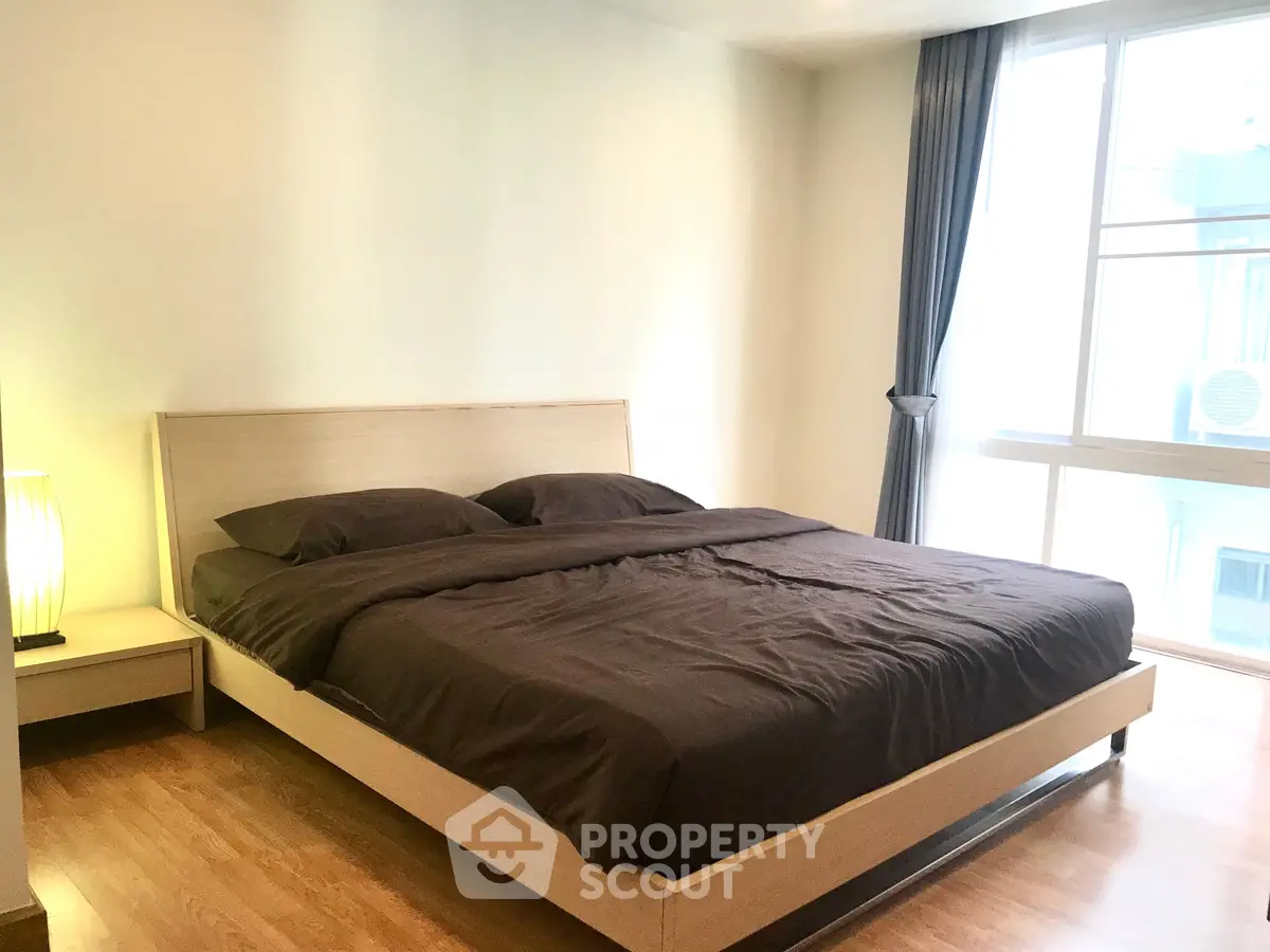 Spacious bedroom with large window and modern furnishings