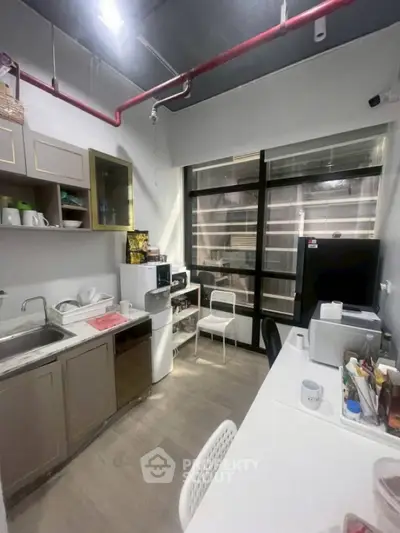 Cozy office kitchenette with modern appliances and ample storage space.