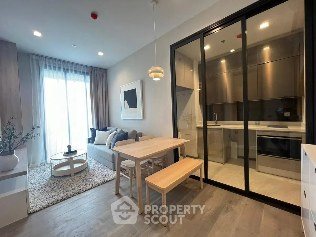 Modern living room with open kitchen, stylish decor, and natural light.