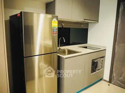 Modern compact kitchen with stainless steel fridge and sleek cabinetry