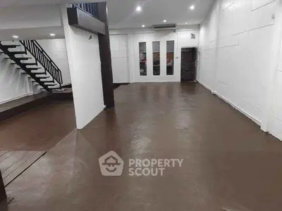Spacious open-plan interior with modern staircase and ample lighting.