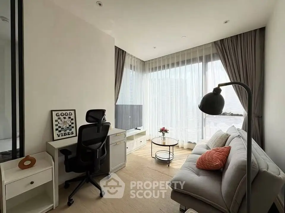 Modern living room with cozy sofa, work desk, and large windows offering natural light.