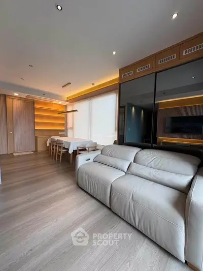 Modern living room with elegant dining area and cozy sofa, featuring warm lighting and sleek wooden flooring.