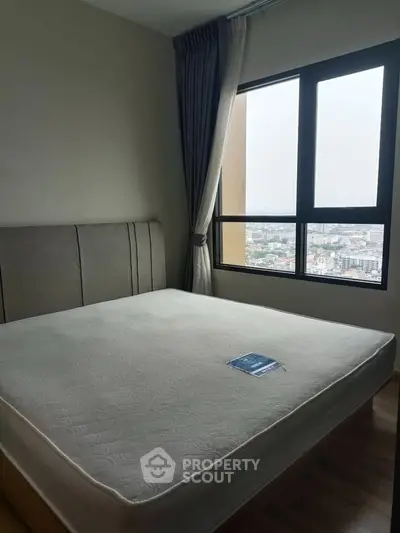 Spacious bedroom with large window offering stunning city views