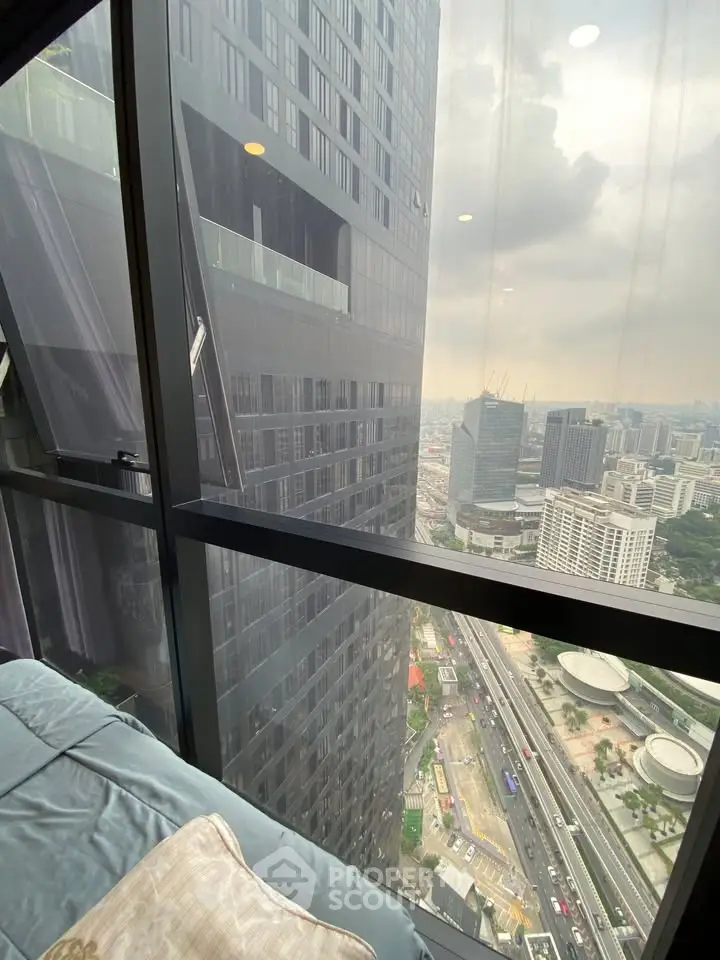 Stunning high-rise city view from a modern apartment window, showcasing urban skyline and bustling streets below.