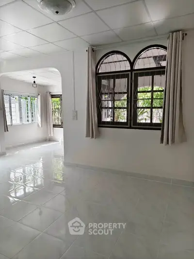Spacious and bright living area with large windows and tiled flooring in a modern home.